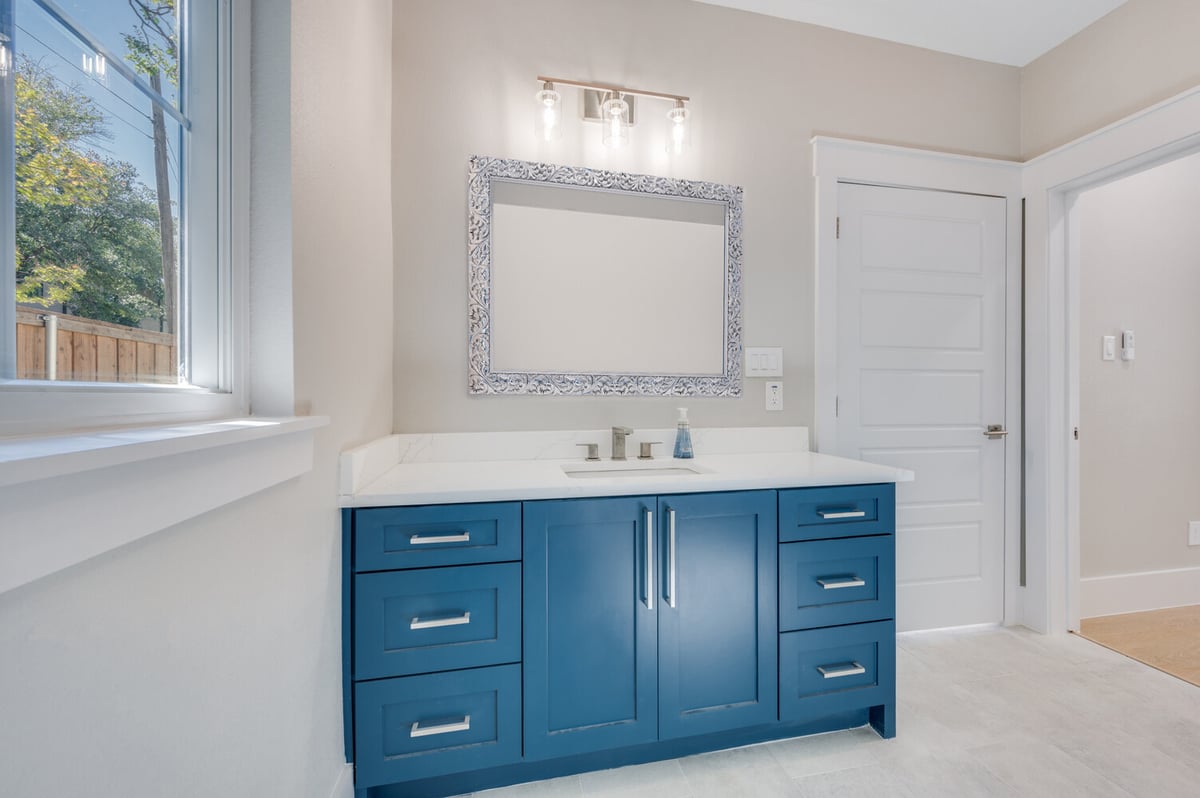 Custom bathroom vanity with bold blue cabinetry and decorative mirror in Dallas ADU by Estate ADU.