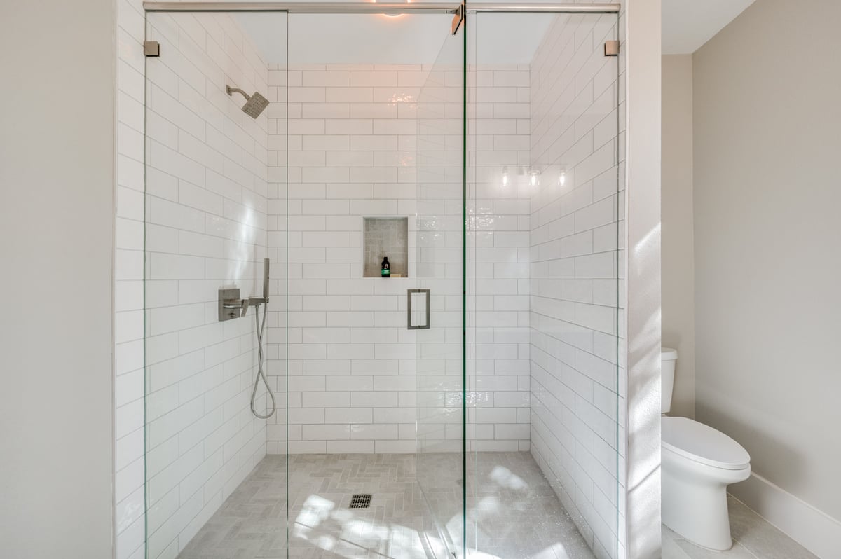 Modern walk-in shower with subway tile and glass enclosure in Dallas ADU bathroom by Estate ADU.