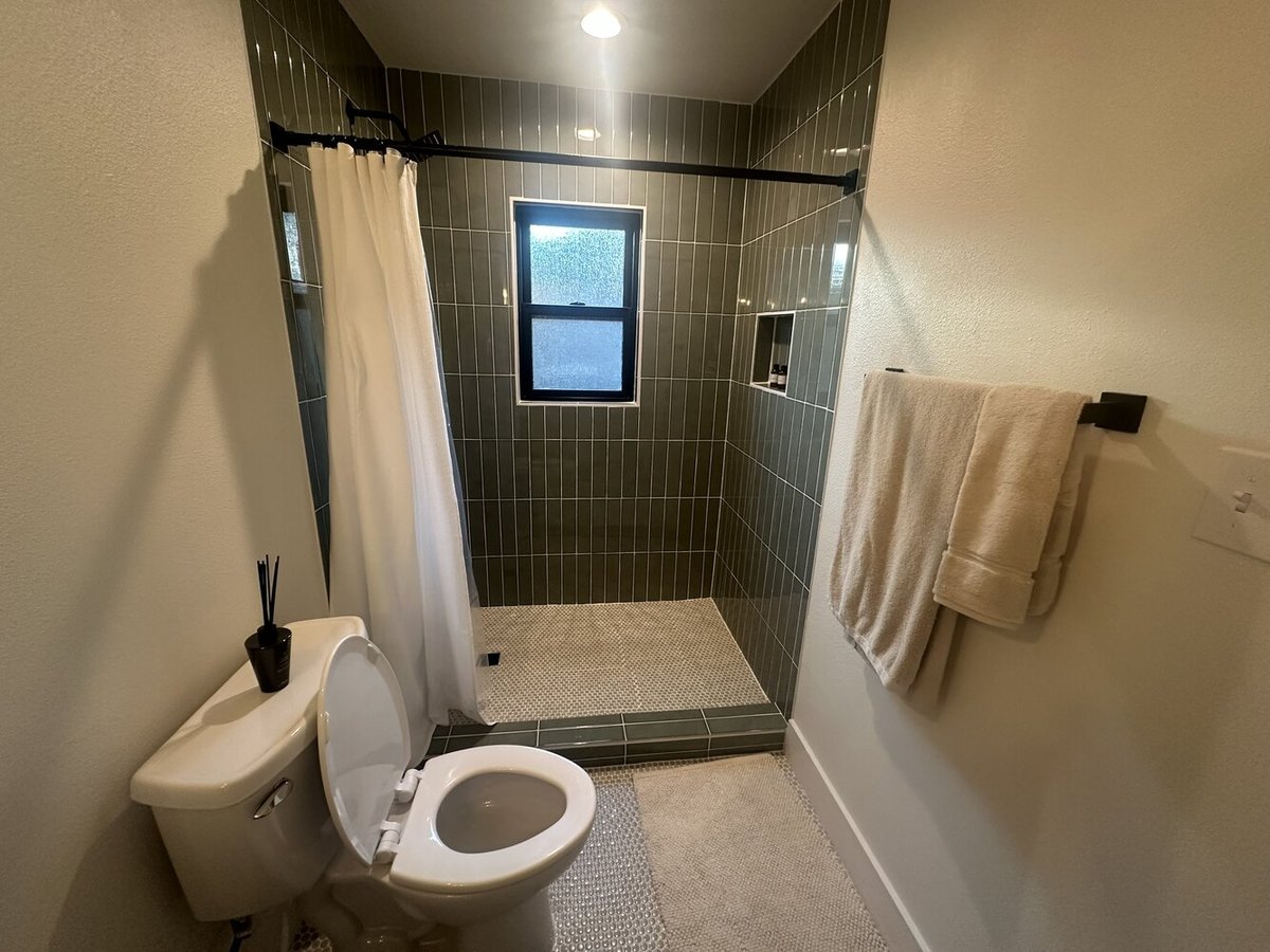 Walk-in shower design with green vertical tile in Dallas ADU bathroom by Estate ADU.