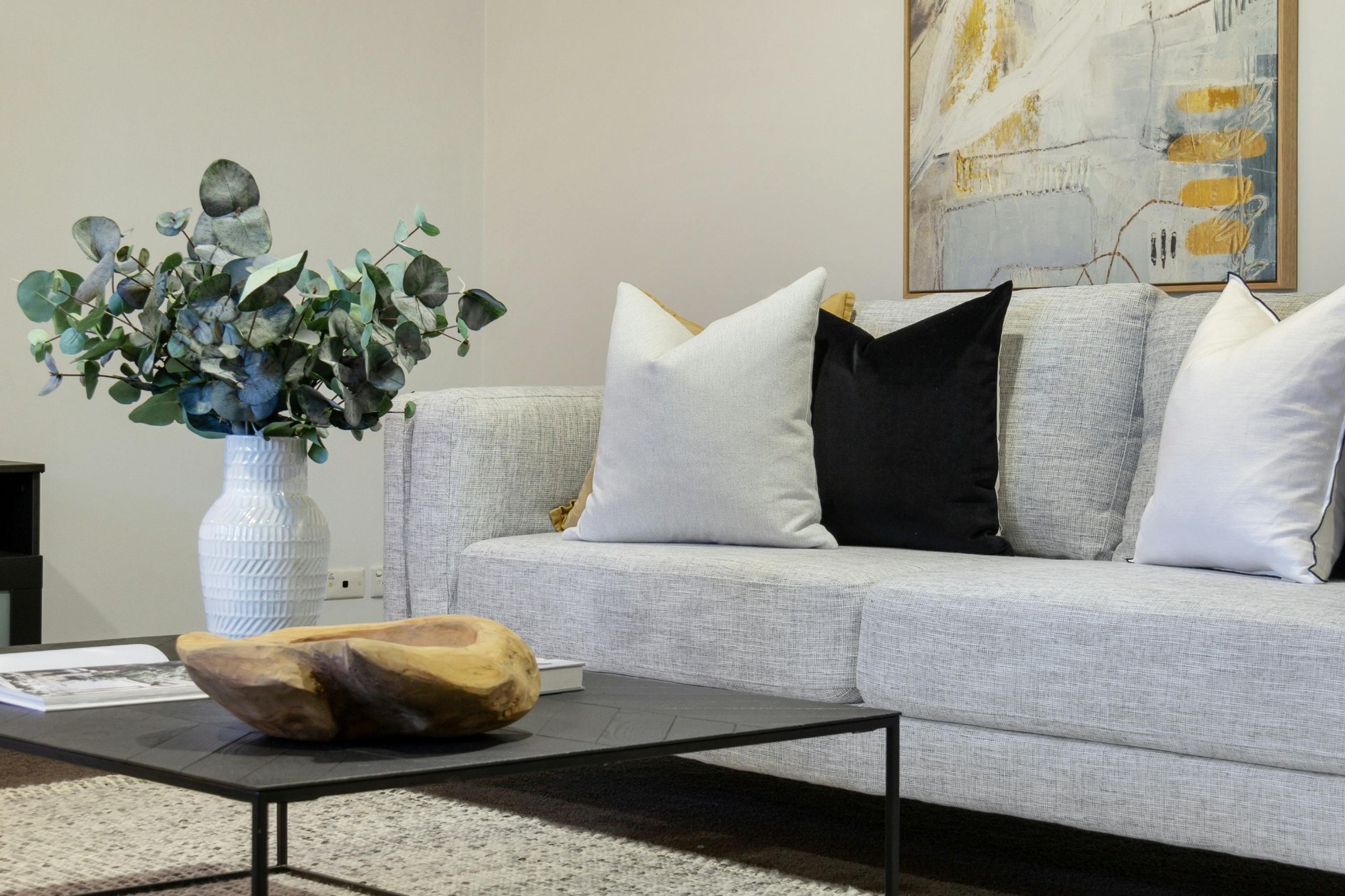 Stock image of a modern living room with light gray sofa neutral pillows and eucalyptus in a white vase